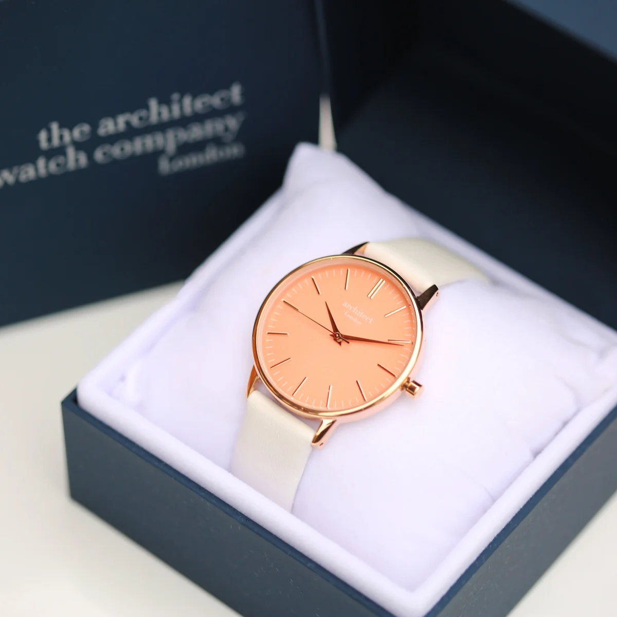 Engraved coral watch with apricot dial and white genuine leather strap displayed on a light background