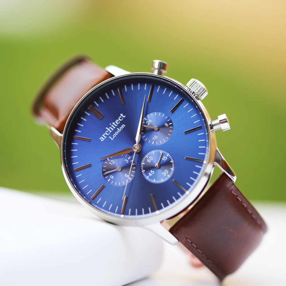 Men's leather strap watch with deep-space blue dial, walnut brown leather band, and three chronograph subdials