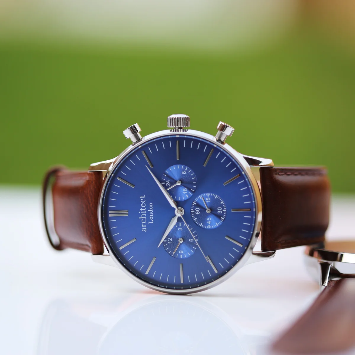 Architect Motivator watch with deep-space blue dial, three chronograph subdials, and walnut brown leather strap on white background