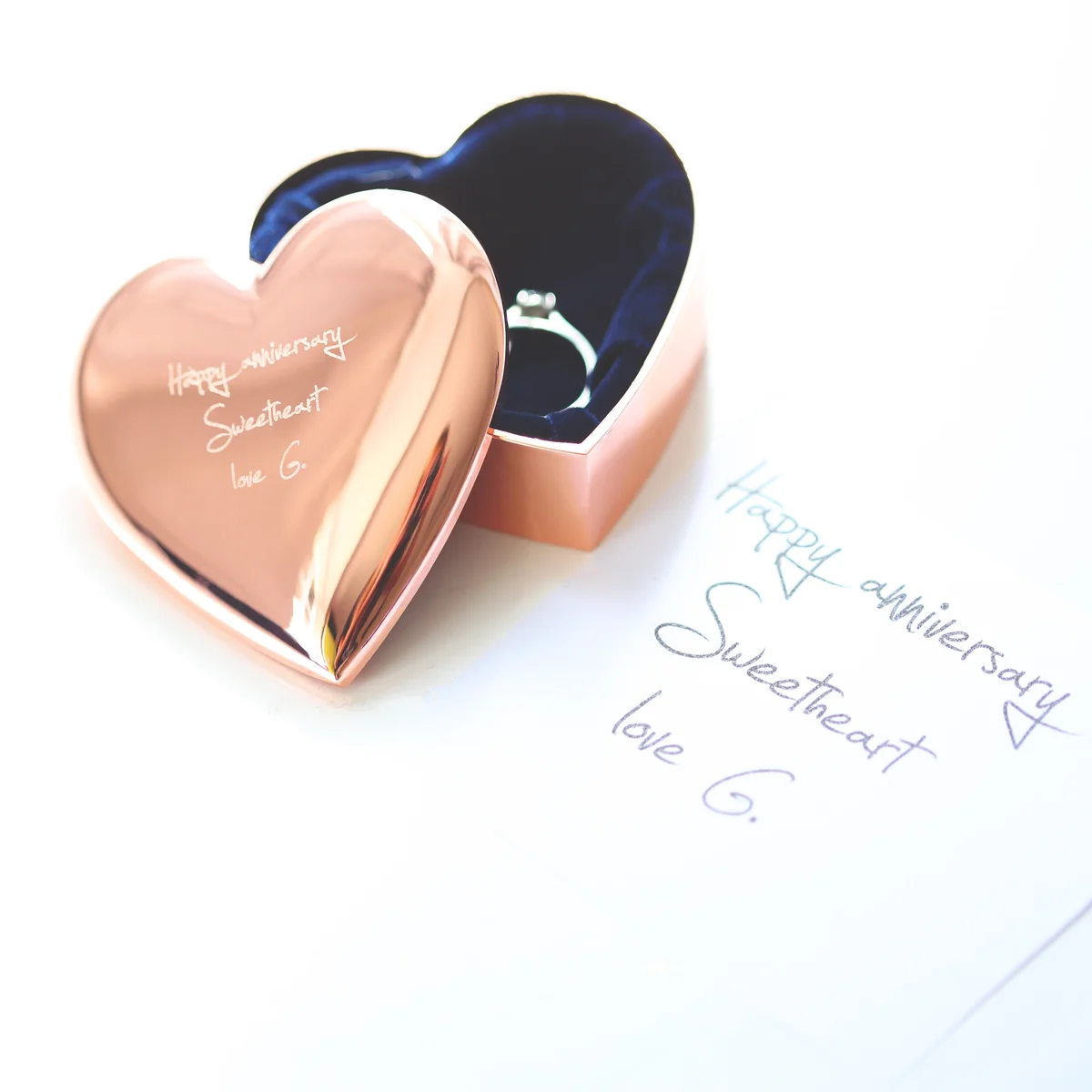 Rose gold heart-shaped engraved jewellery box with personalised handwriting on highly polished surface, open showing interior space