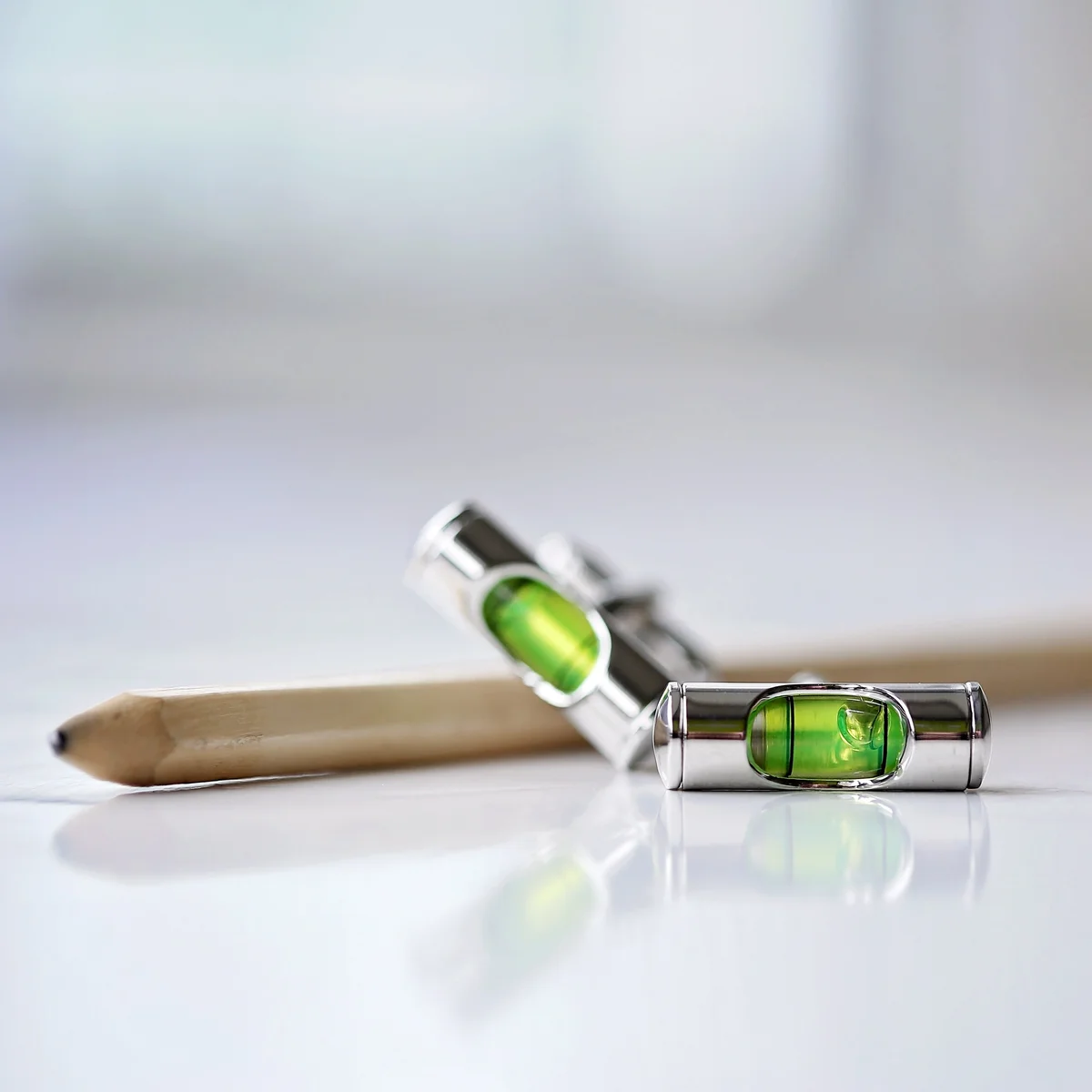Pair of spirit level cufflinks with visible liquid vials displayed next to an engraved luxury gift box