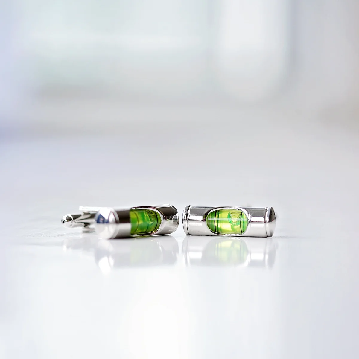 Pair of spirit level cufflinks with liquid detail displayed next to a personalised cufflinks gift engraved box