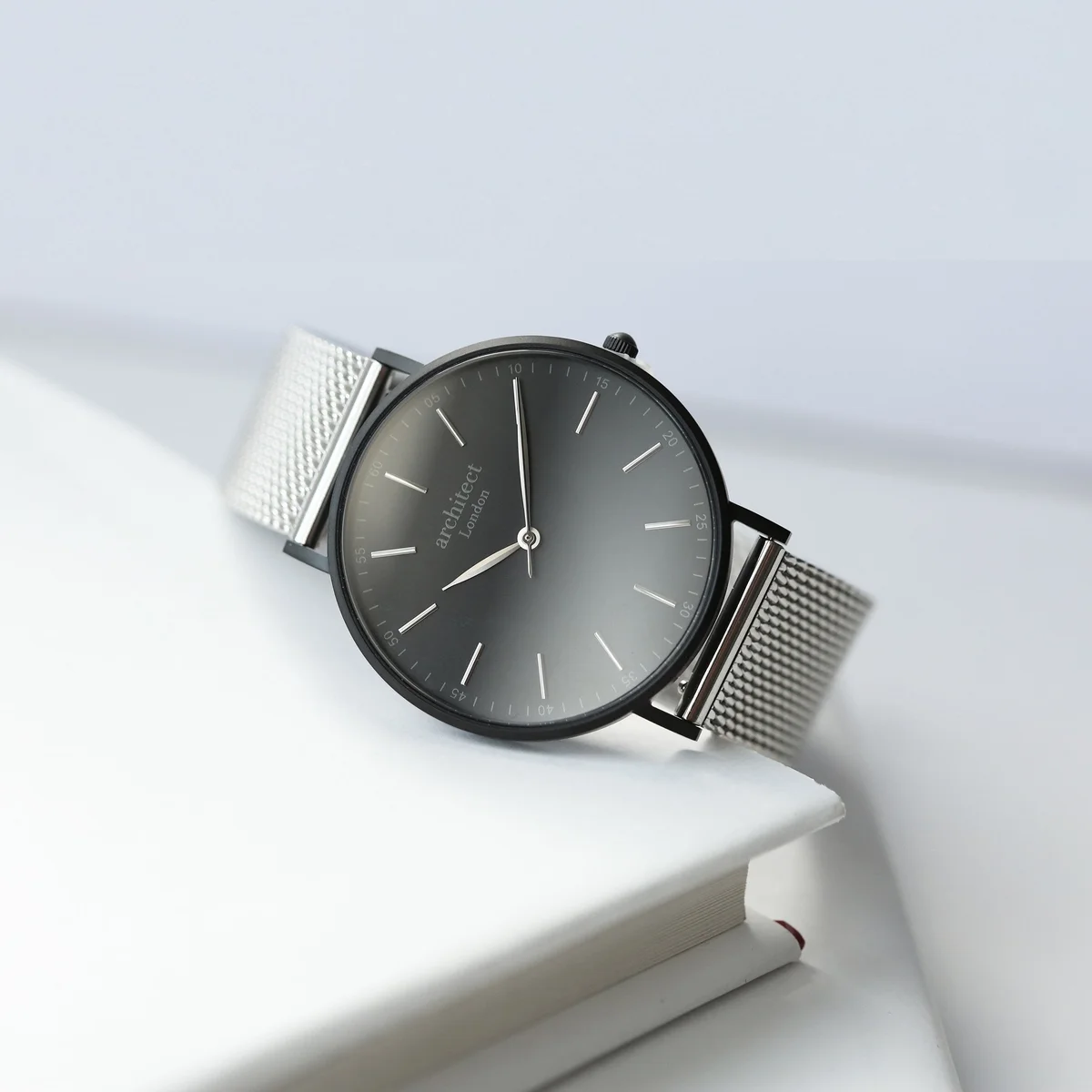 Men's minimalist watch with silver stainless steel mesh strap and modern font engraving on brushed steel case