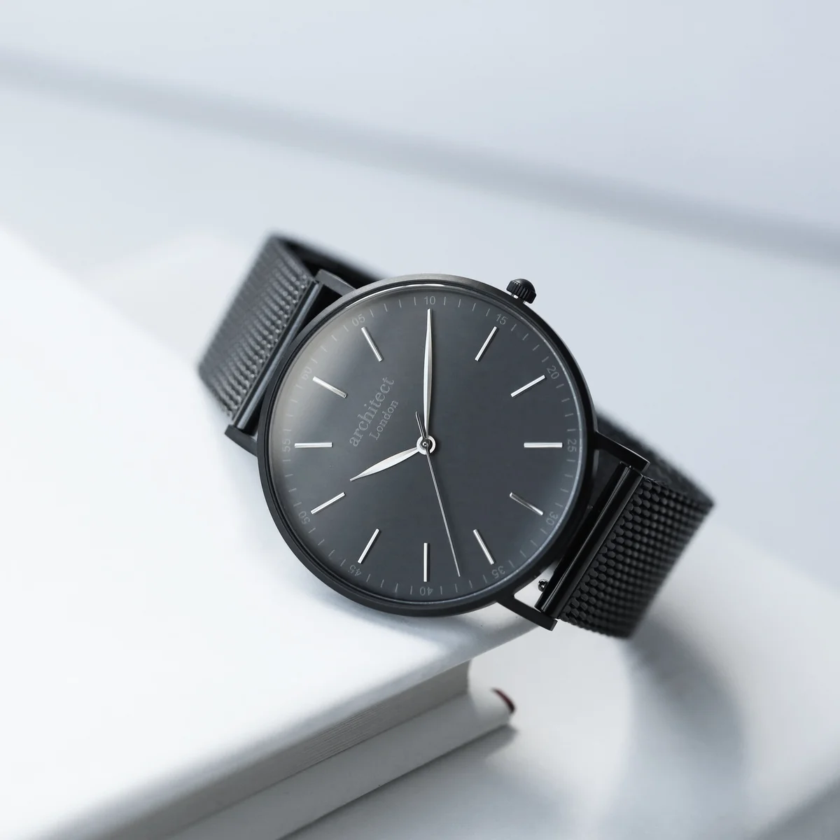 Engraved men's watch with pitch black mesh strap and brushed stainless steel case on a white background