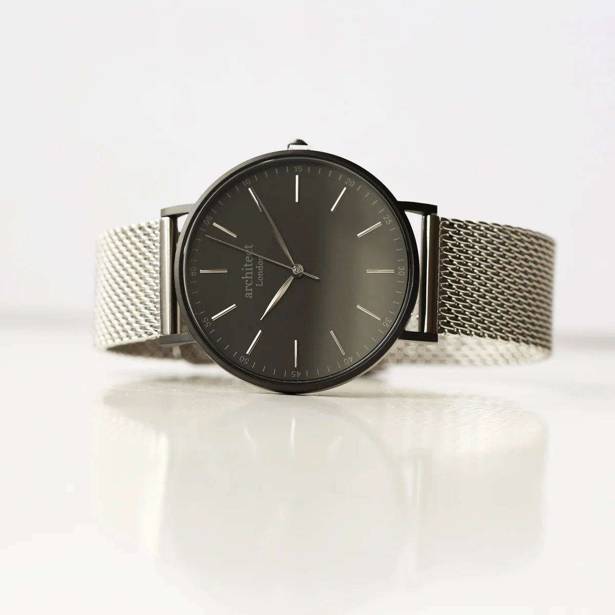 Men’s minimalist silver mesh strap watch with brushed stainless steel case and clean dial on white background