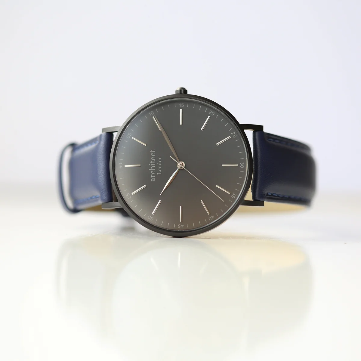 Engraved men's watch with minimalist dial, stainless steel case, and admiral blue genuine leather strap on white background