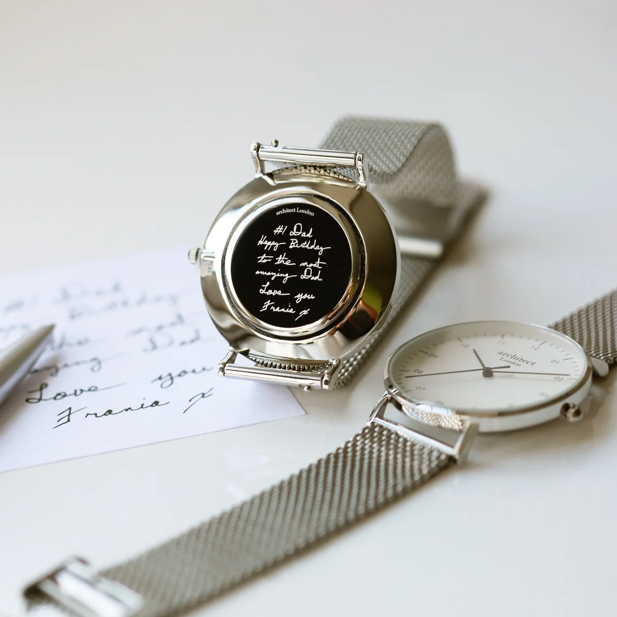 Mens minimalist watch with polished stainless steel case and silver mesh strap, featuring handwriting engraving on back