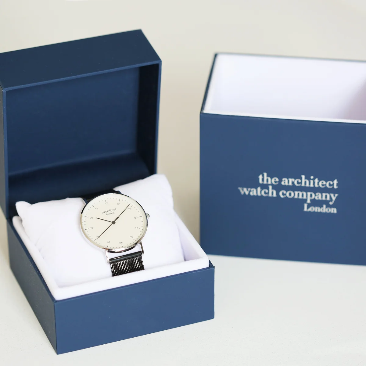 Men's minimalist watch with pitch black mesh strap and polished stainless steel case shown on wrist close-up