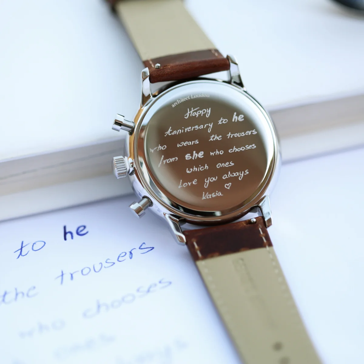 Engraved men's watch with deep-space blue dial, walnut brown leather strap, and three chronograph subdials on white background