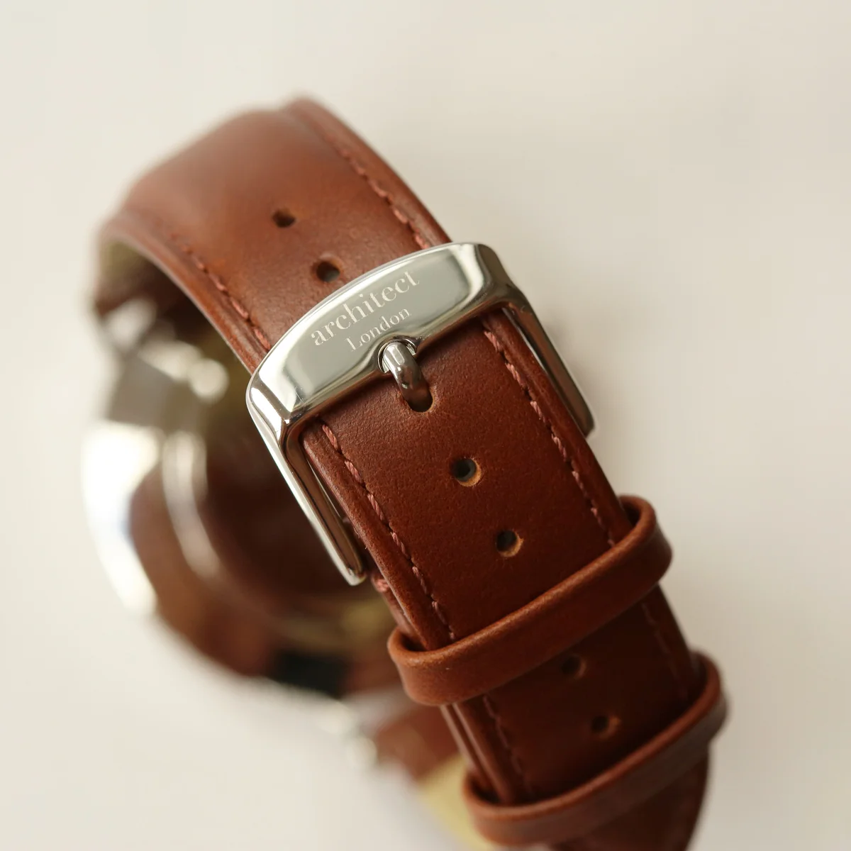 Engraved men's watch with modern font on stainless steel case and walnut leather strap, displayed on white background