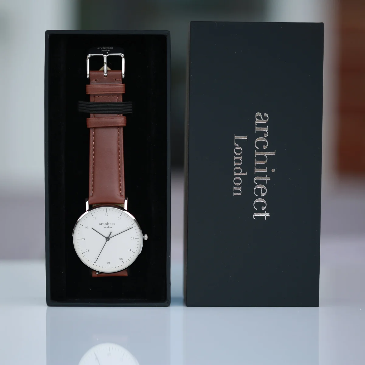 Men's minimalist watch with gunmetal stainless steel case, walnut leather strap, and engraved modern font backplate