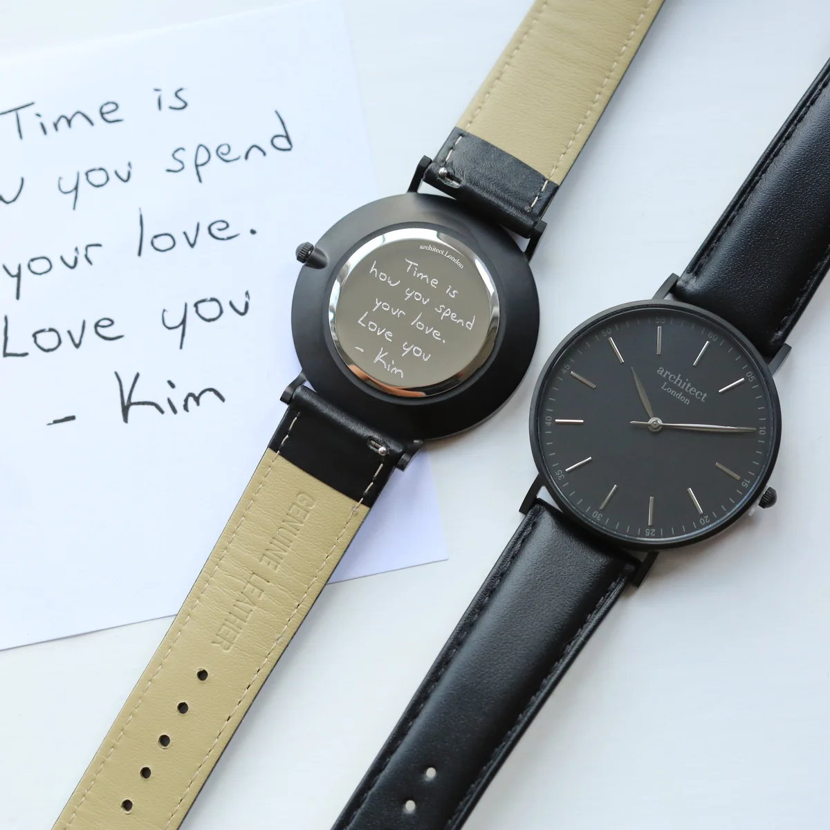 Personalised men's watch with minimalist black dial, jet black leather strap, and stainless steel case on white background