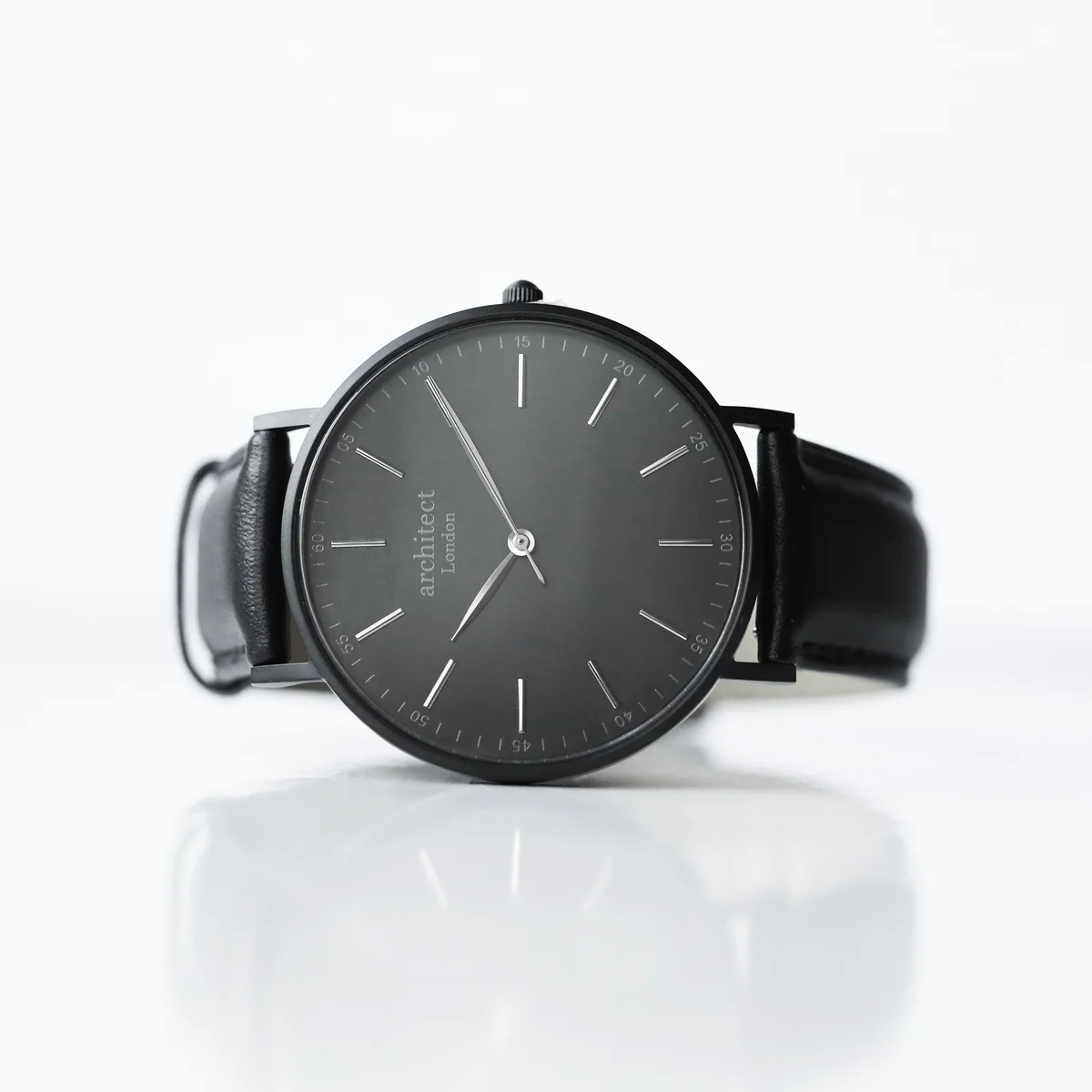 Men’s minimalist leather strap watch with jet black genuine leather band and brushed stainless steel case shown on wrist