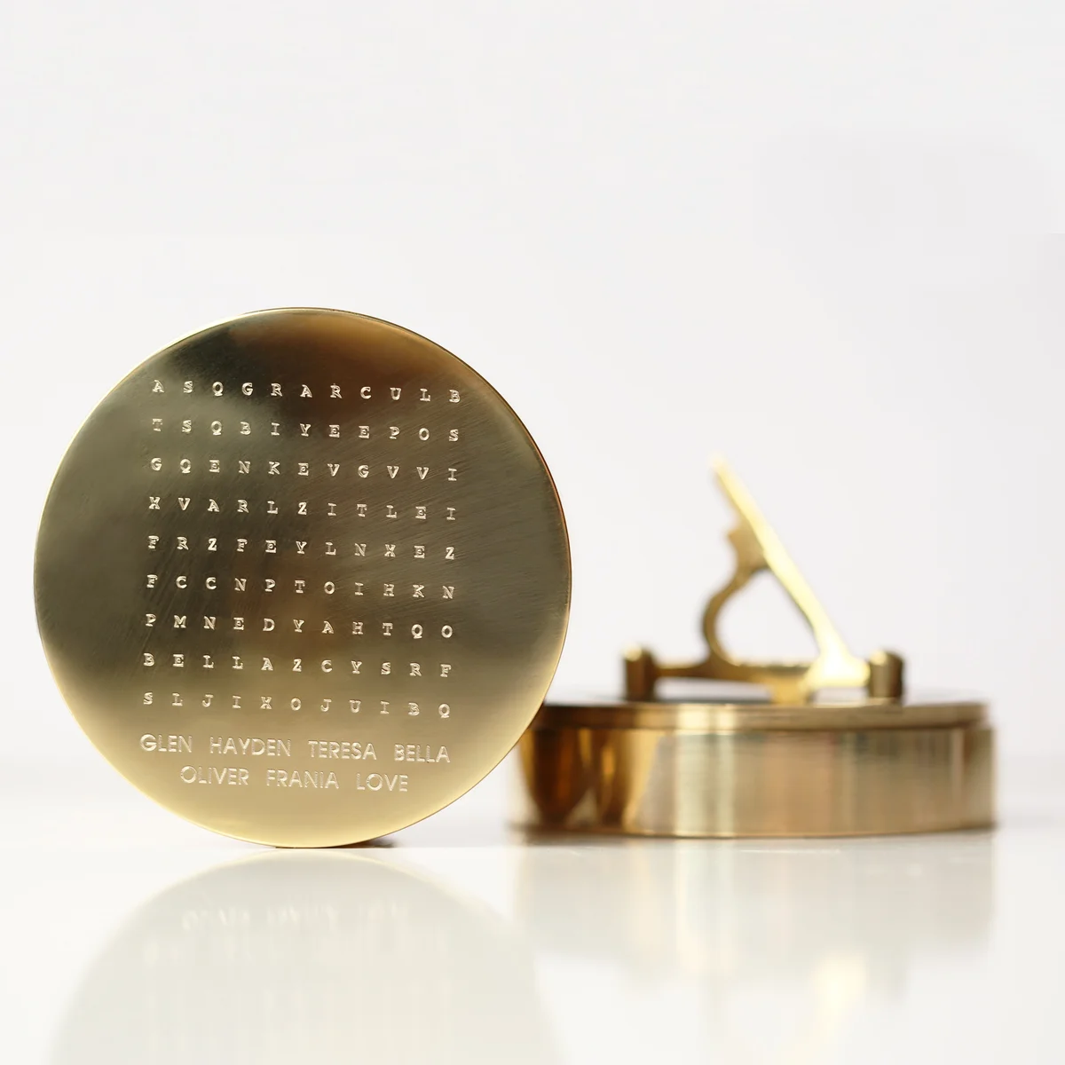 Personalised brass sundial compass with engraved hidden words, nautical design, and protective pouch on white background