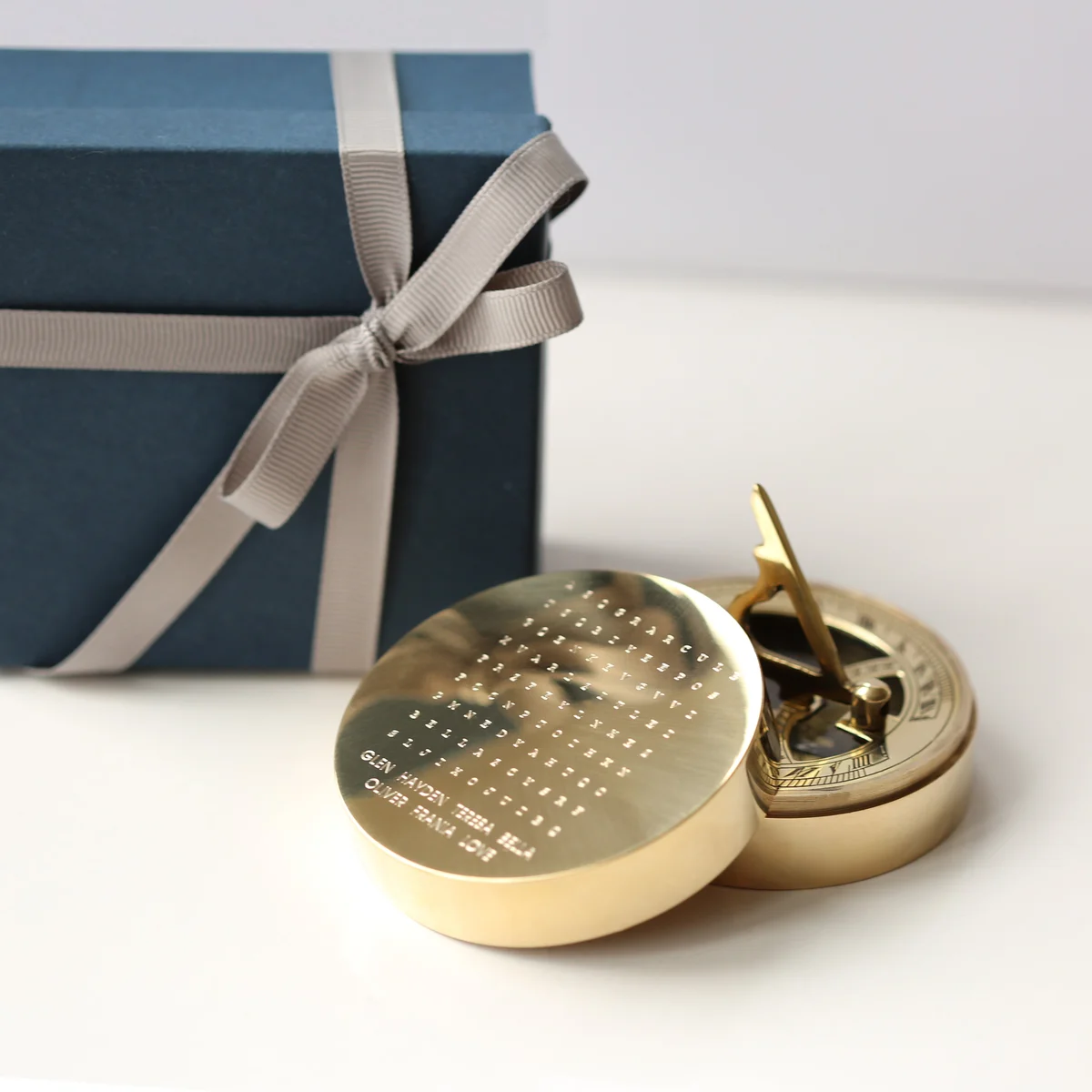 Brass nautical sundial compass with engraved hidden words, displayed with protective pouch and gift box on white background