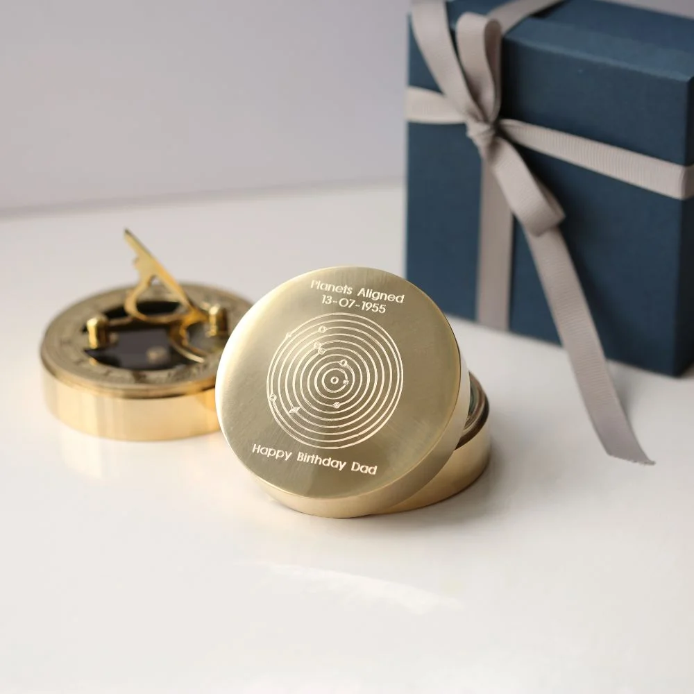 Personalised nautical sundial compass in brass with engraved planets alignment and protective pouch on white background