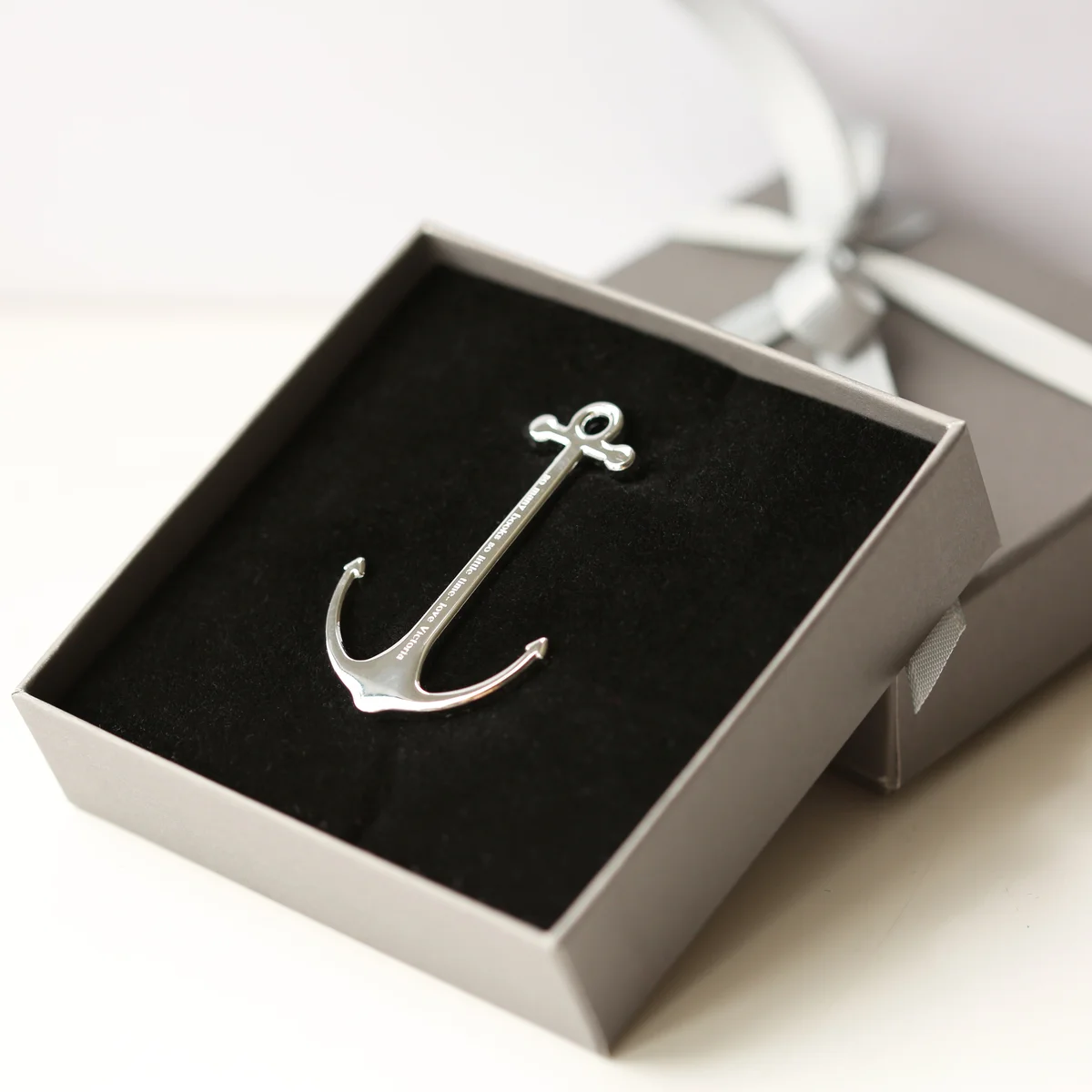 Silver and black personalised book anchor with modern font engraving, polished metal, displayed with gift box on white background