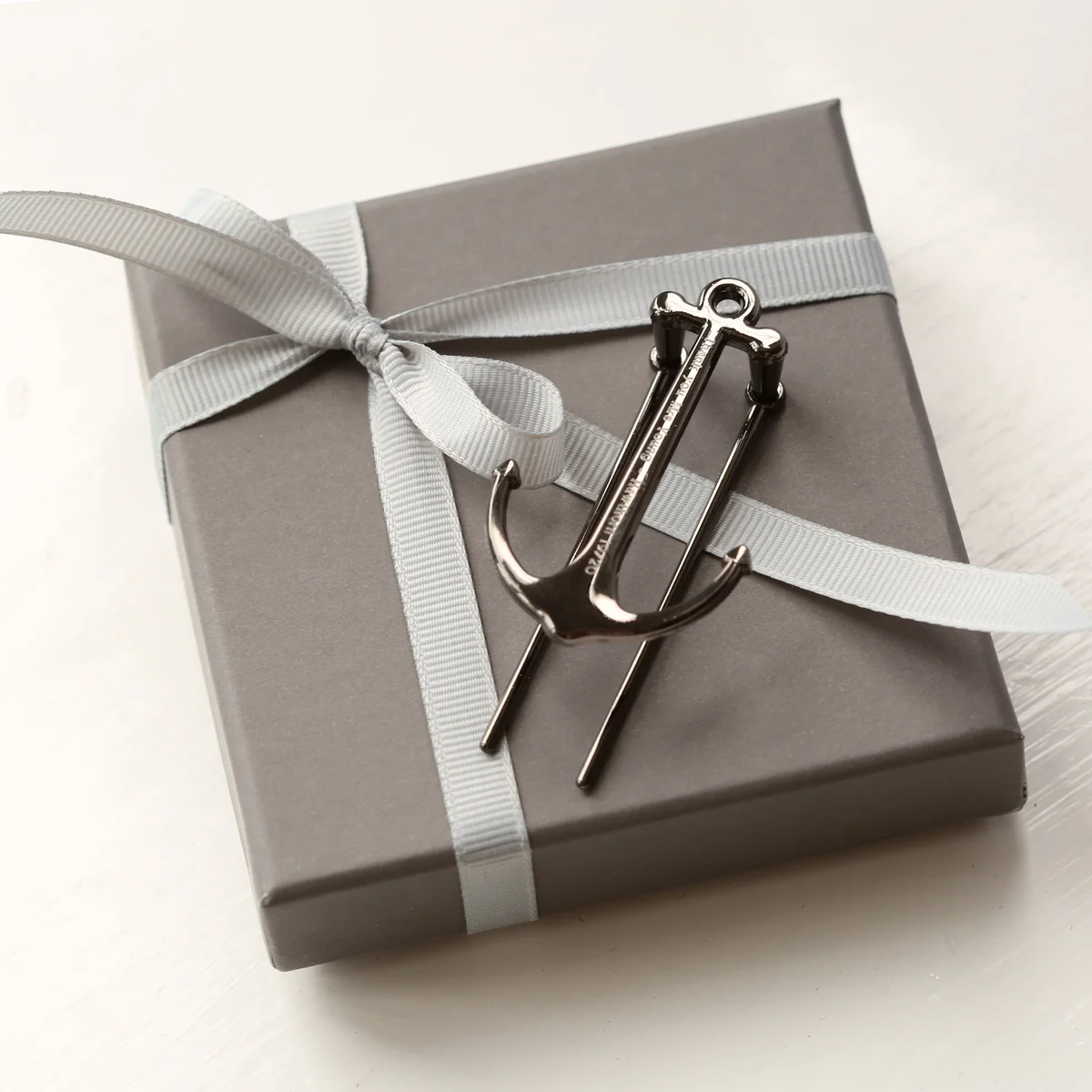 Personalised book anchor in silver and black polished metal with engraved message, displayed in a gift box on white background
