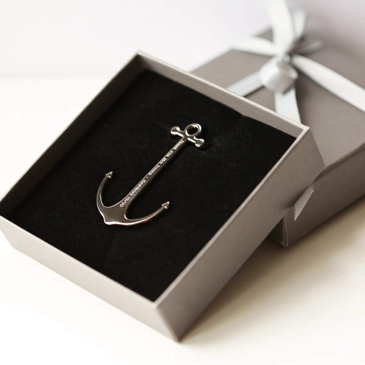 Personalised book anchor in silver and black polished metal with engraved modern font, displayed with gift box on white background