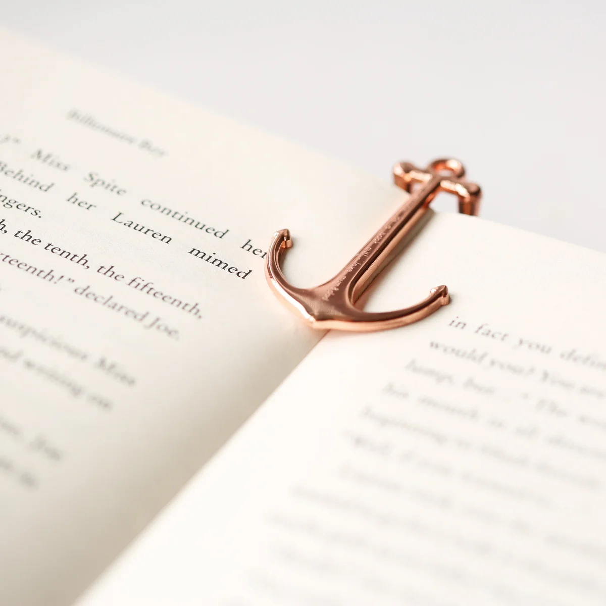 Personalised book anchor in gold and rose gold polished metal with modern font engraving on a gift box background