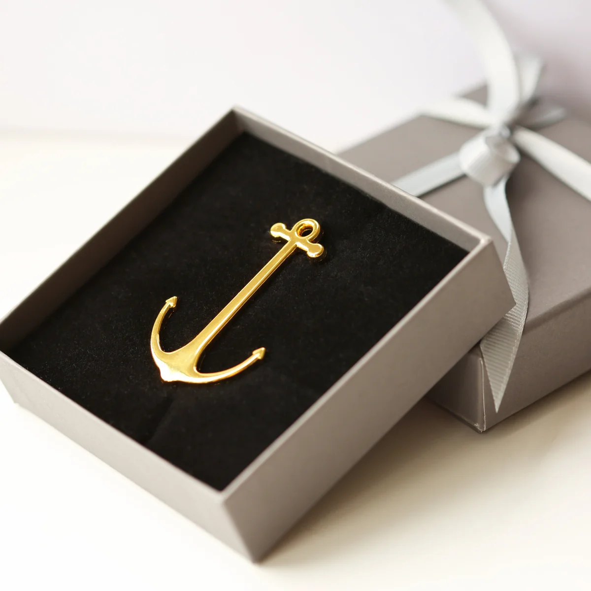 Gold and rose gold personalised book anchor holding open a book, polished metal with engraved modern font, in gift box