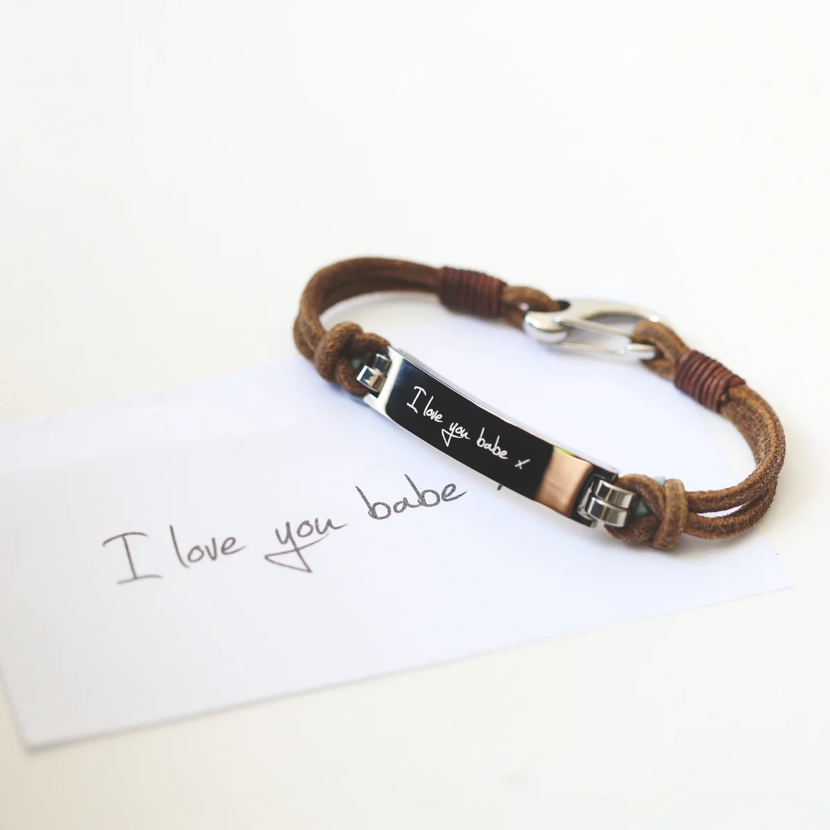 Tan genuine leather men's bracelet with engraved handwriting and snap-lock clasp on white background