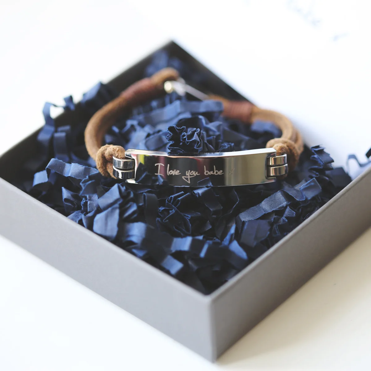 Tan genuine leather men's bracelet with engraved handwriting and snap-lock clasp on a white background