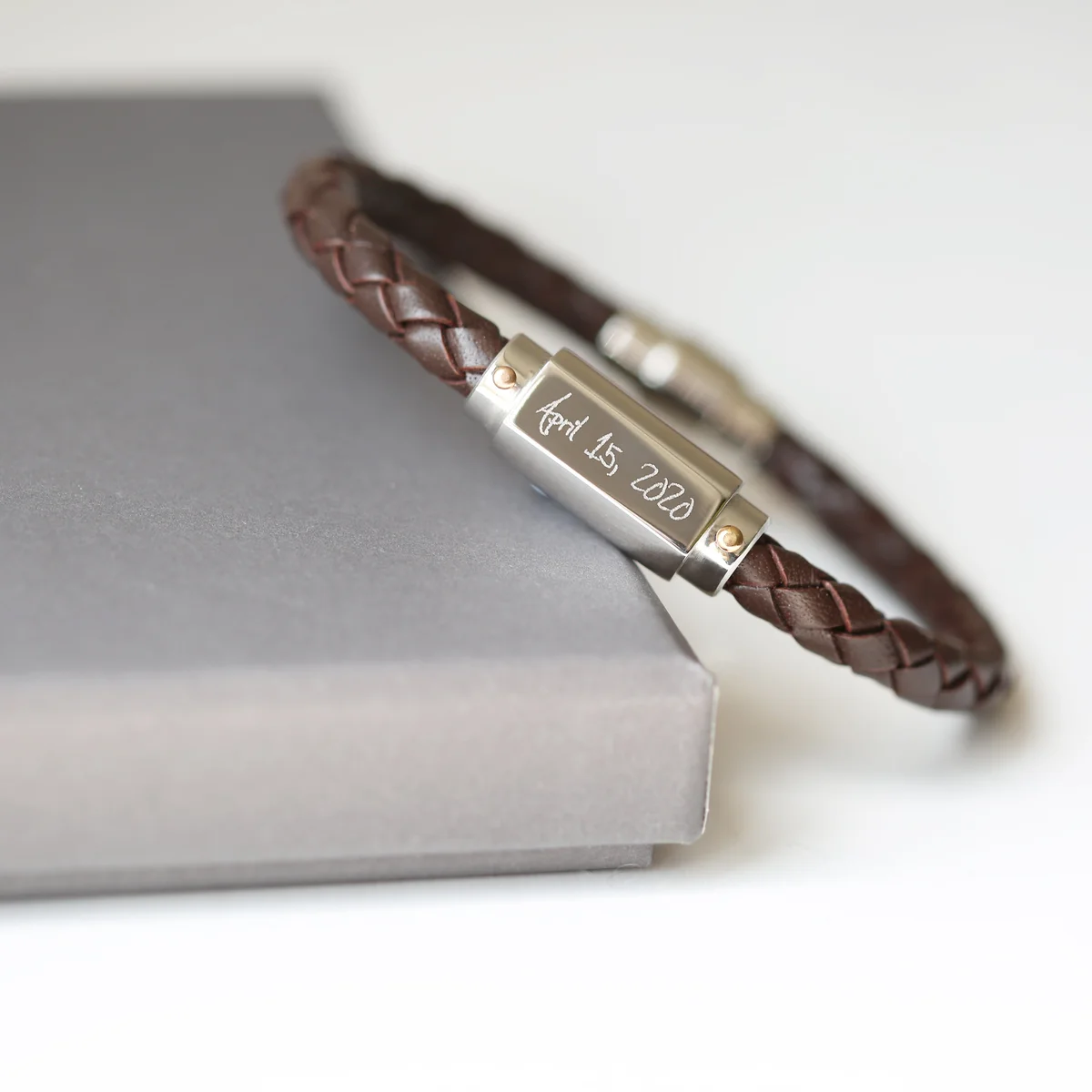 Twisted genuine leather engraved men's bracelet with magnetic snap-lock clasp in stainless steel on white background