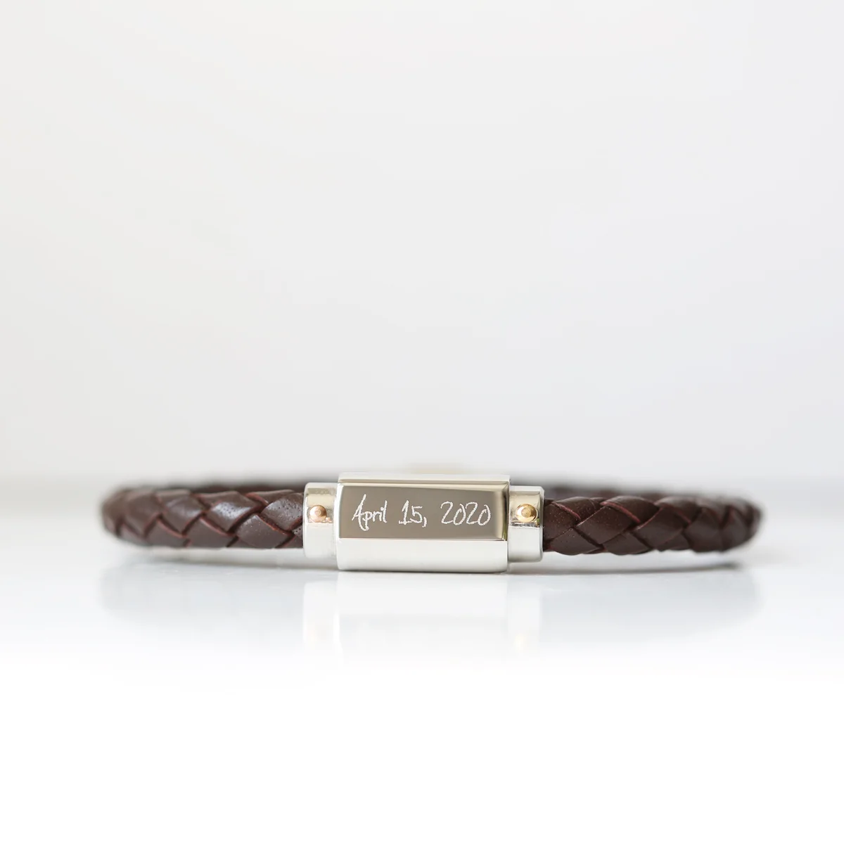 Close-up of personalised twisted leather bracelet with magnetic snap-lock clasp and handwriting engraving on stainless steel plate