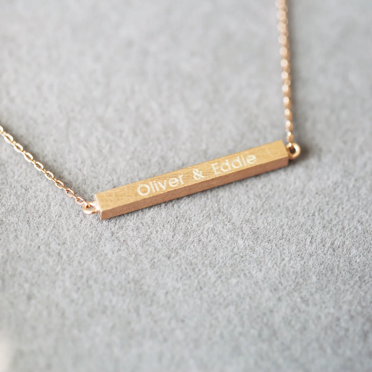 Silver necklace with horizontal engraved bar pendant on adjustable chain, displayed on a white background with gift box