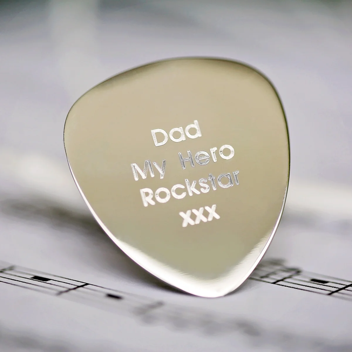 Personalised guitar pick made of polished stainless steel with engraved modern font in gift box with blue shred and ribbon