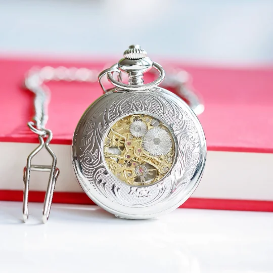 Engraved pocket watch with skeleton view, Roman numerals, and personalized handwriting on silver case, displayed open in gift box