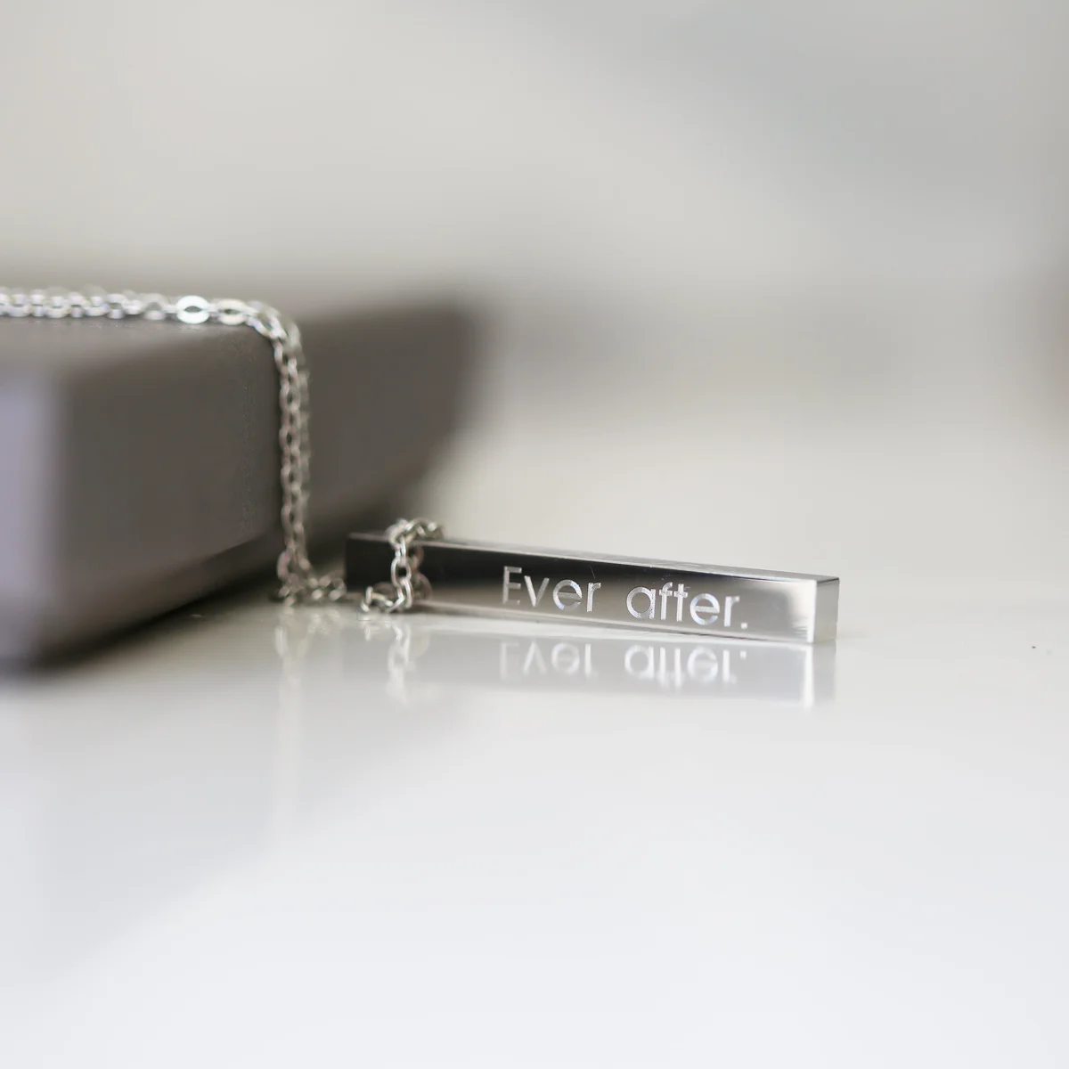 Delicate personalised engraved bar necklace in silver with modern font on a fine chain, displayed on white background