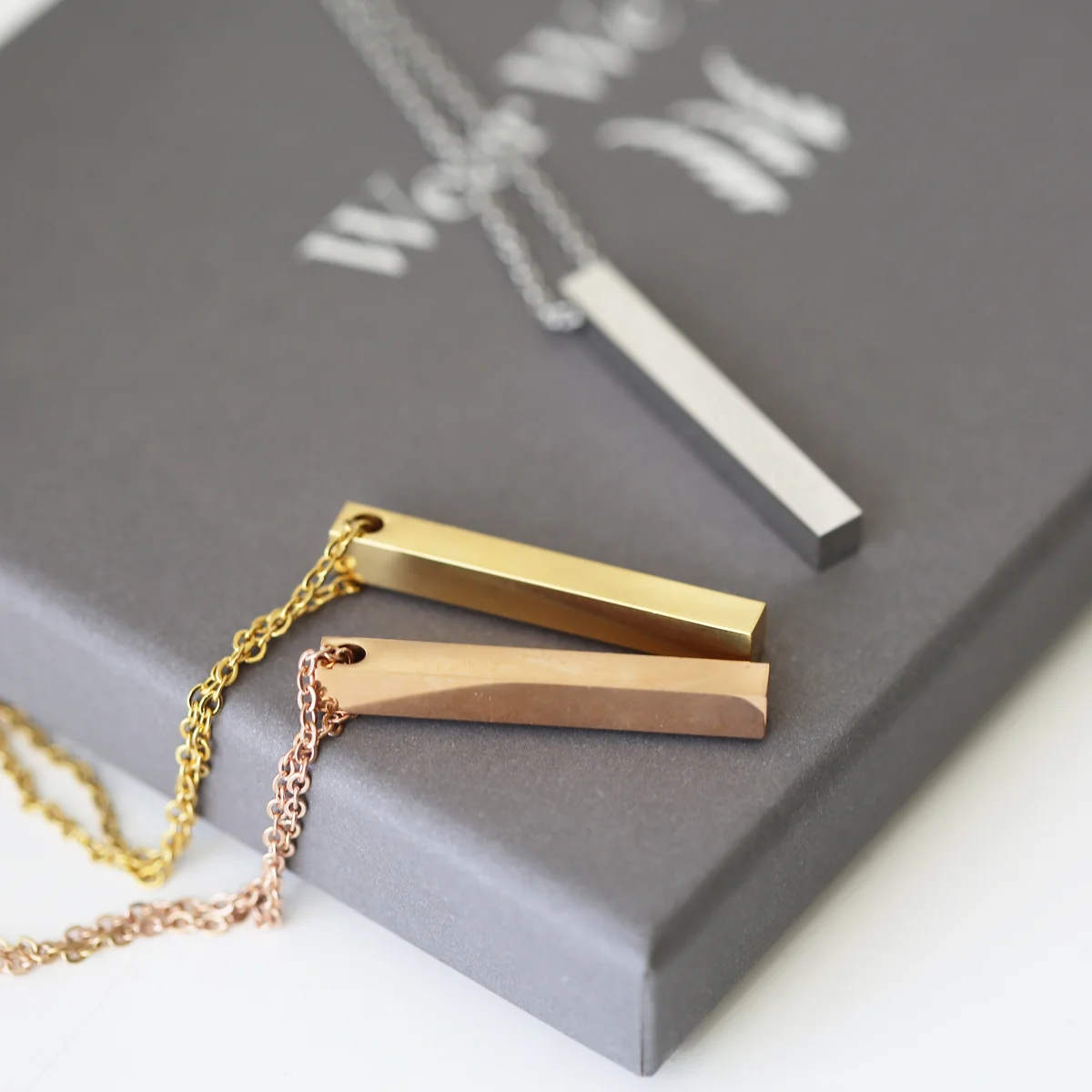 Personalised bar necklace in rose gold with delicate engraving displayed on a white gift box background