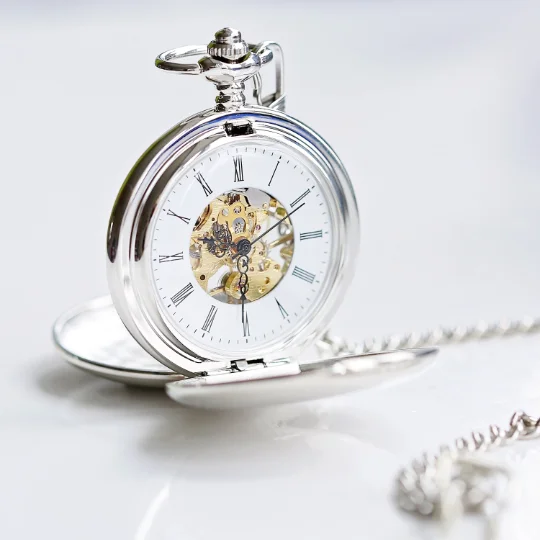 Engraved pocket watch with dual opening, skeleton view showing mechanical movement, in a gift box with ribbon