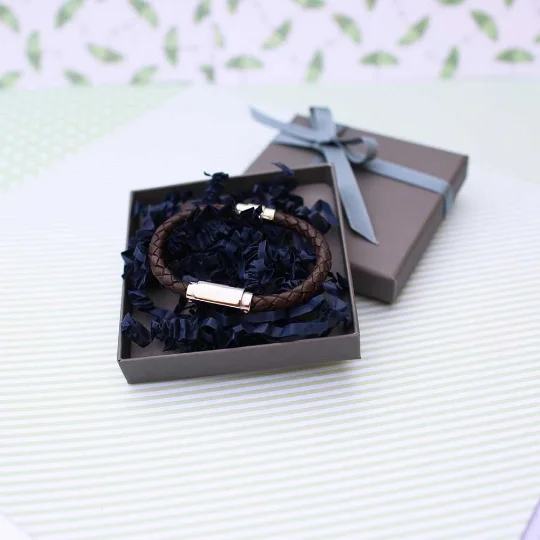 Close-up of personalised twisted leather bracelet with magnetic snap-lock clasp and engraved stainless steel plate