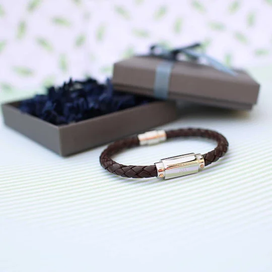 Personalised twisted leather bracelet with engraved stainless steel magnetic snap-lock clasp on a white background