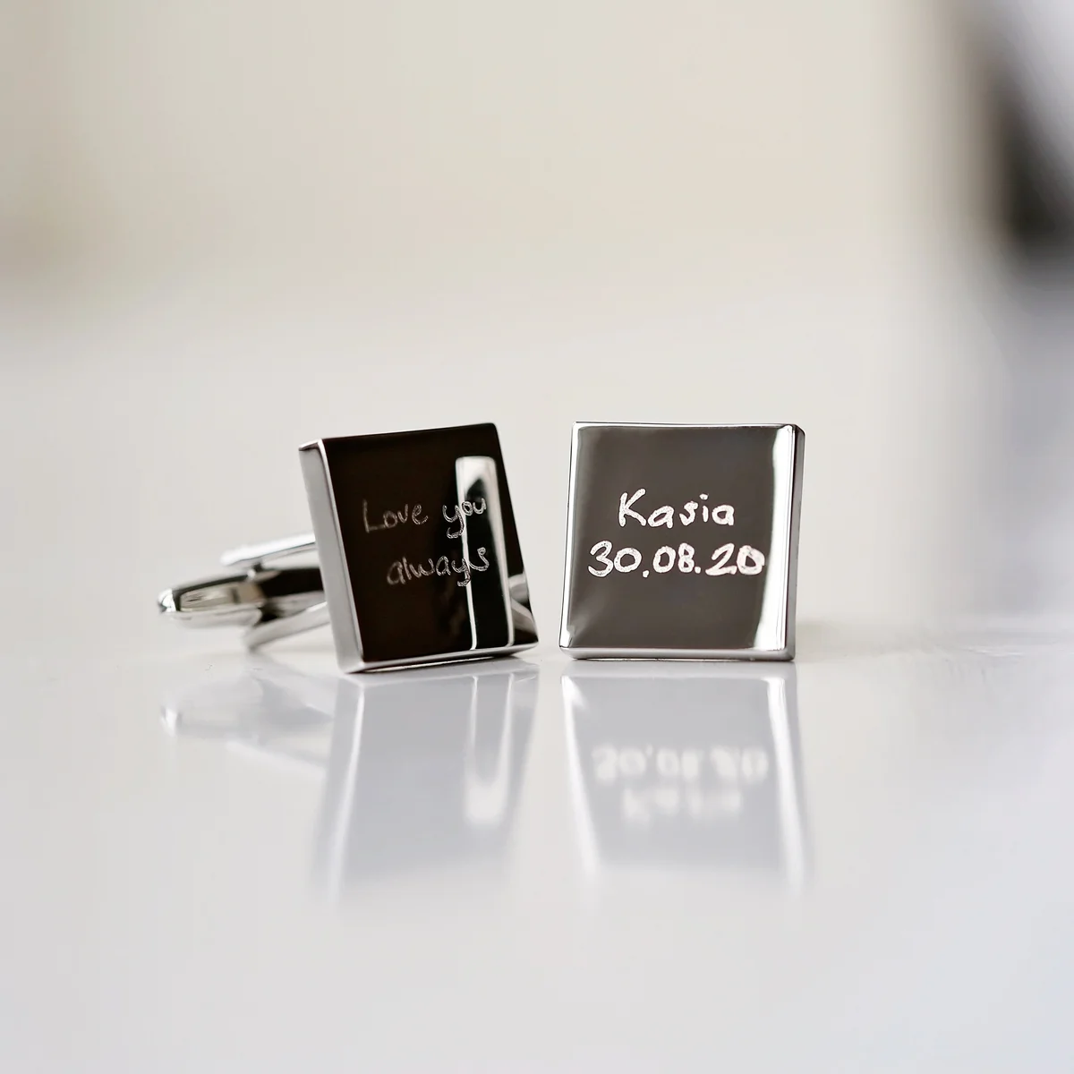 Silver personalised handwriting cufflinks engraved with a child's drawing, displayed on a grey background with gift box nearby
