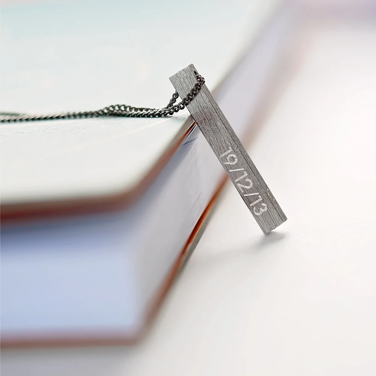 Brushed finish necklace with engraved details displayed in Wear We Met gift box with blue zig-zag shred lining