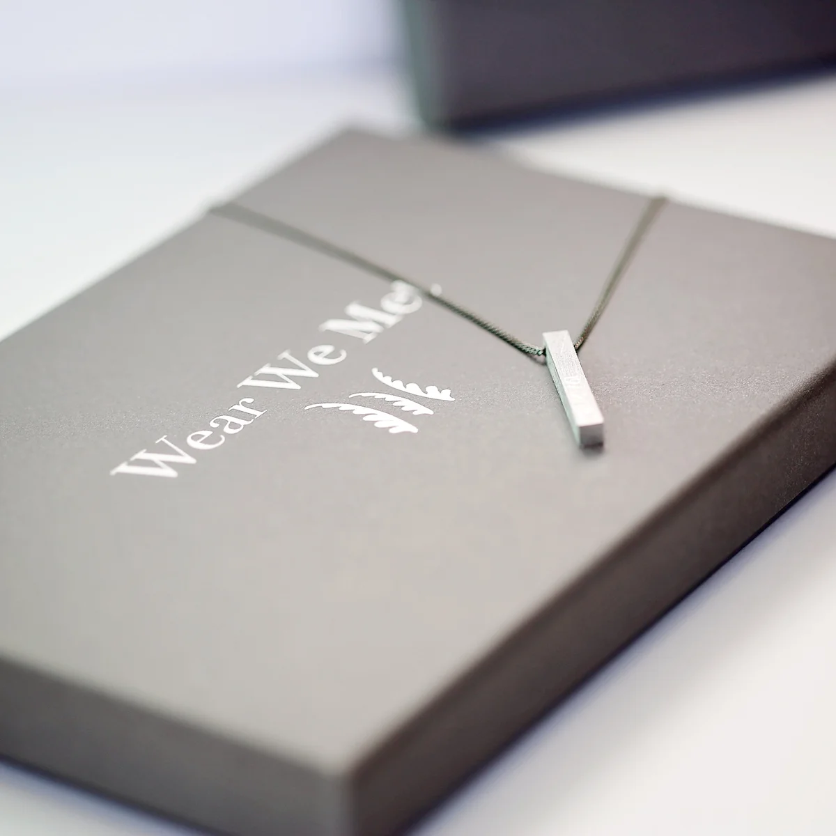 Brushed finish personalised men's gift necklace with engraved coordinates displayed on a wooden surface next to gift box