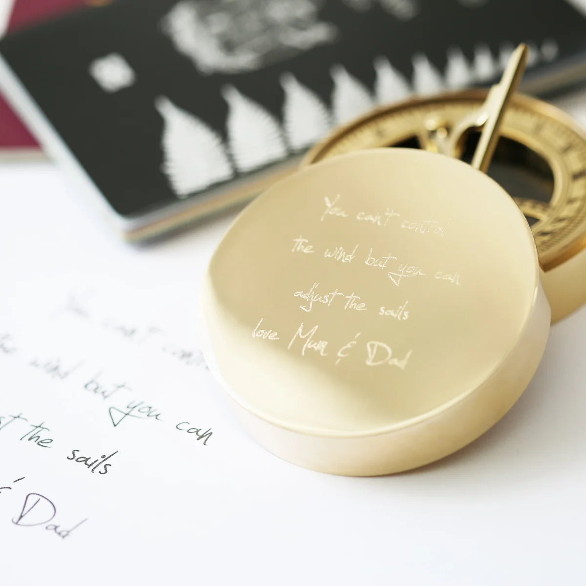 Brass sundial compass with personalised handwriting engraving, shown with protective pouch and gift box on white background