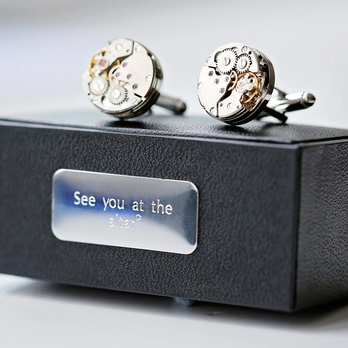Pair of stainless steel gear movement cufflinks with visible moving parts on a white background