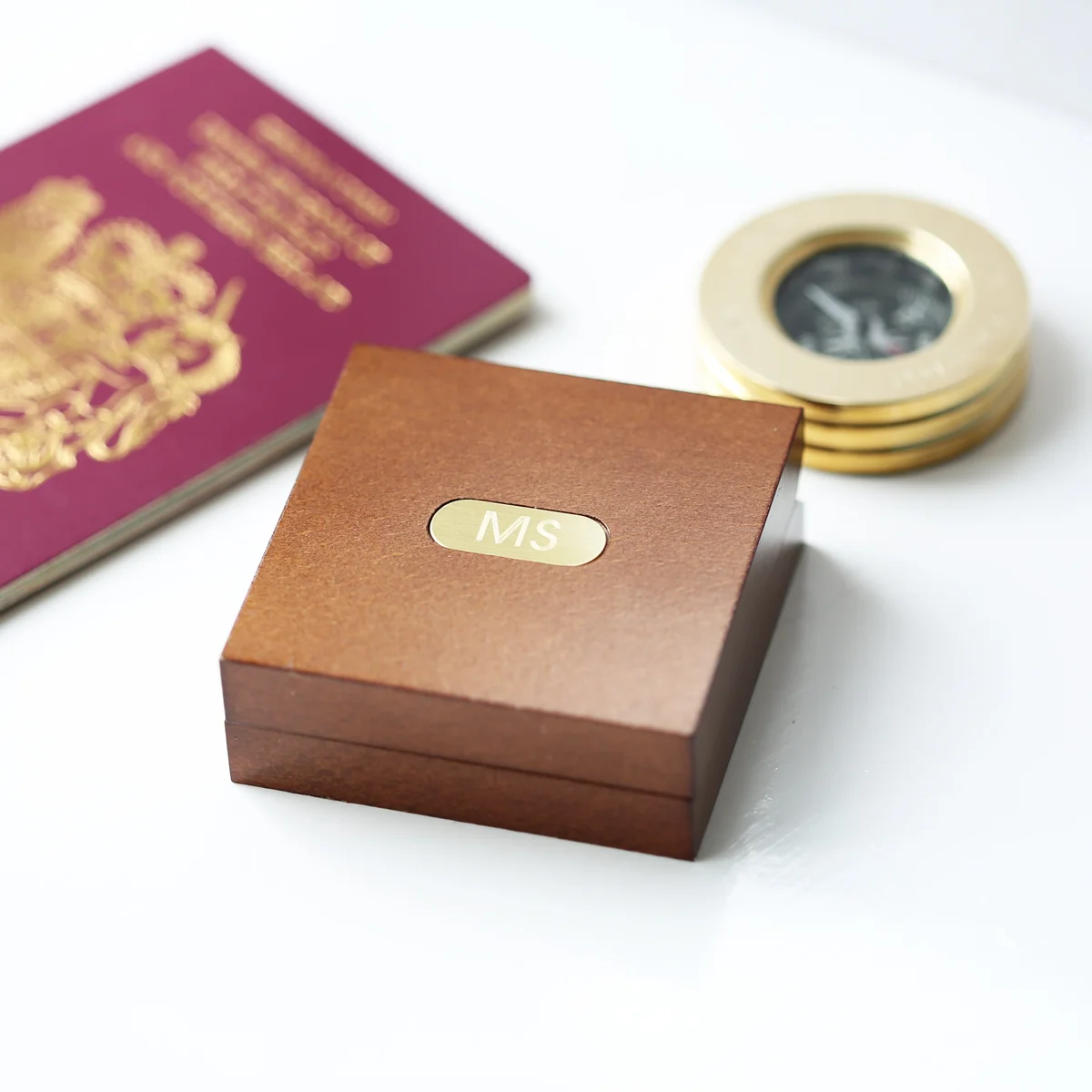 Brass compass with personalised engraving inside an open mahogany timber box with a monogrammed plate and ribbon