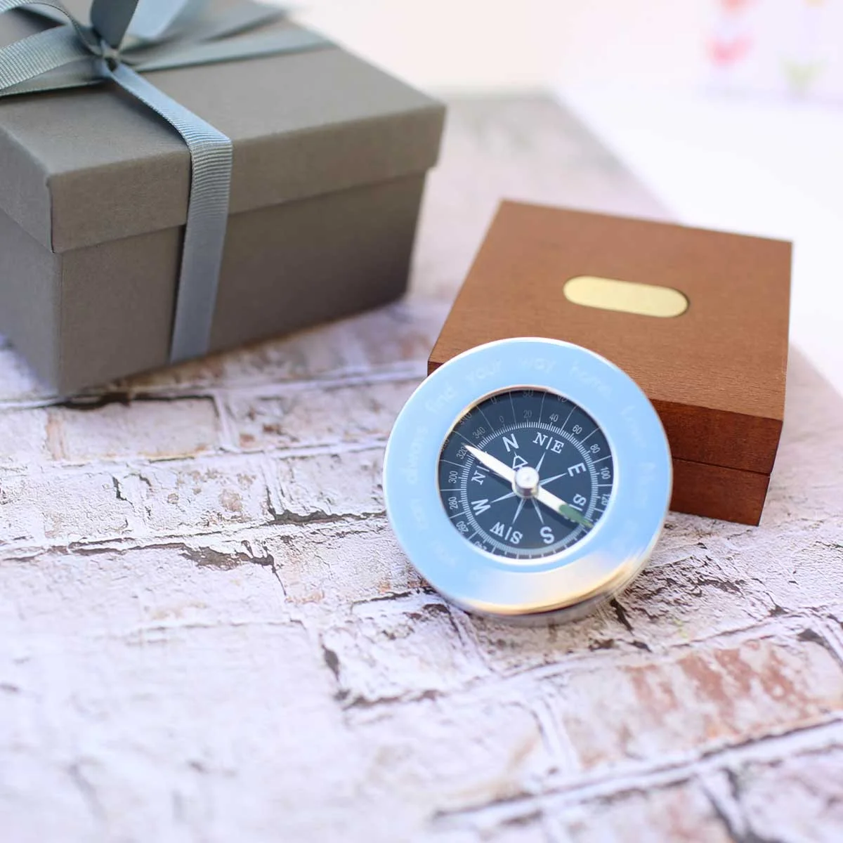 Brass compass keepsake with engraved modern font inside an open mahogany timber box with monogrammed plate and ribbon