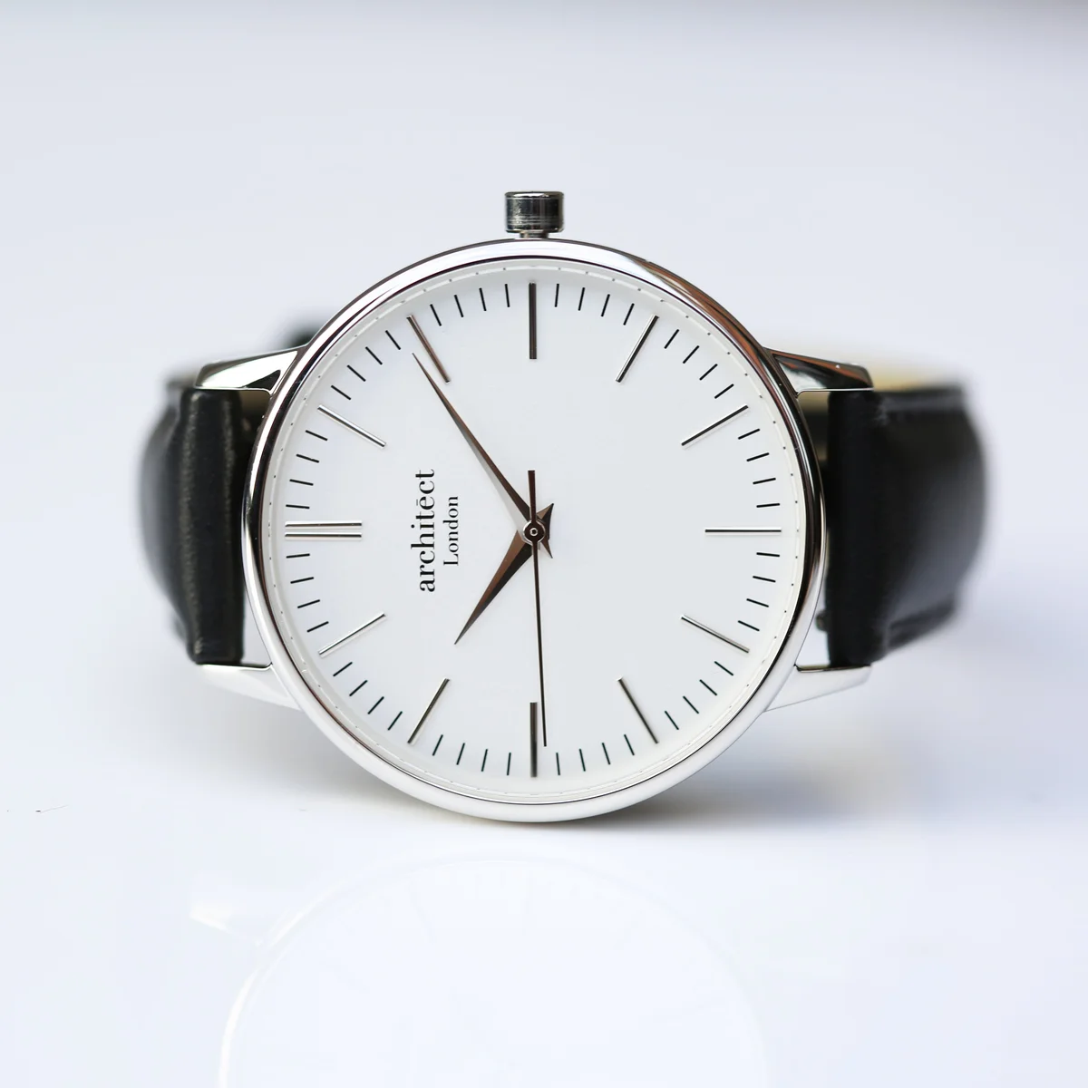 Ladies silver bezel watch with minimalist white dial and black genuine leather strap on white background