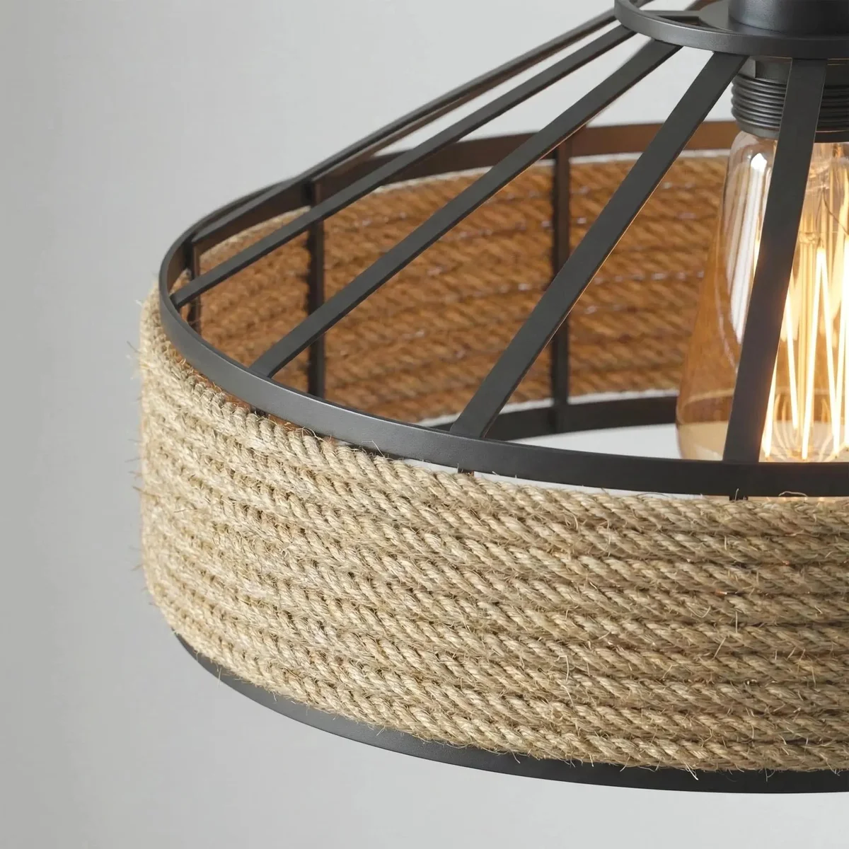 Boho rattan lamp with woven bamboo shade, black metal cage, and twisted hemp rope cord hanging from ceiling
