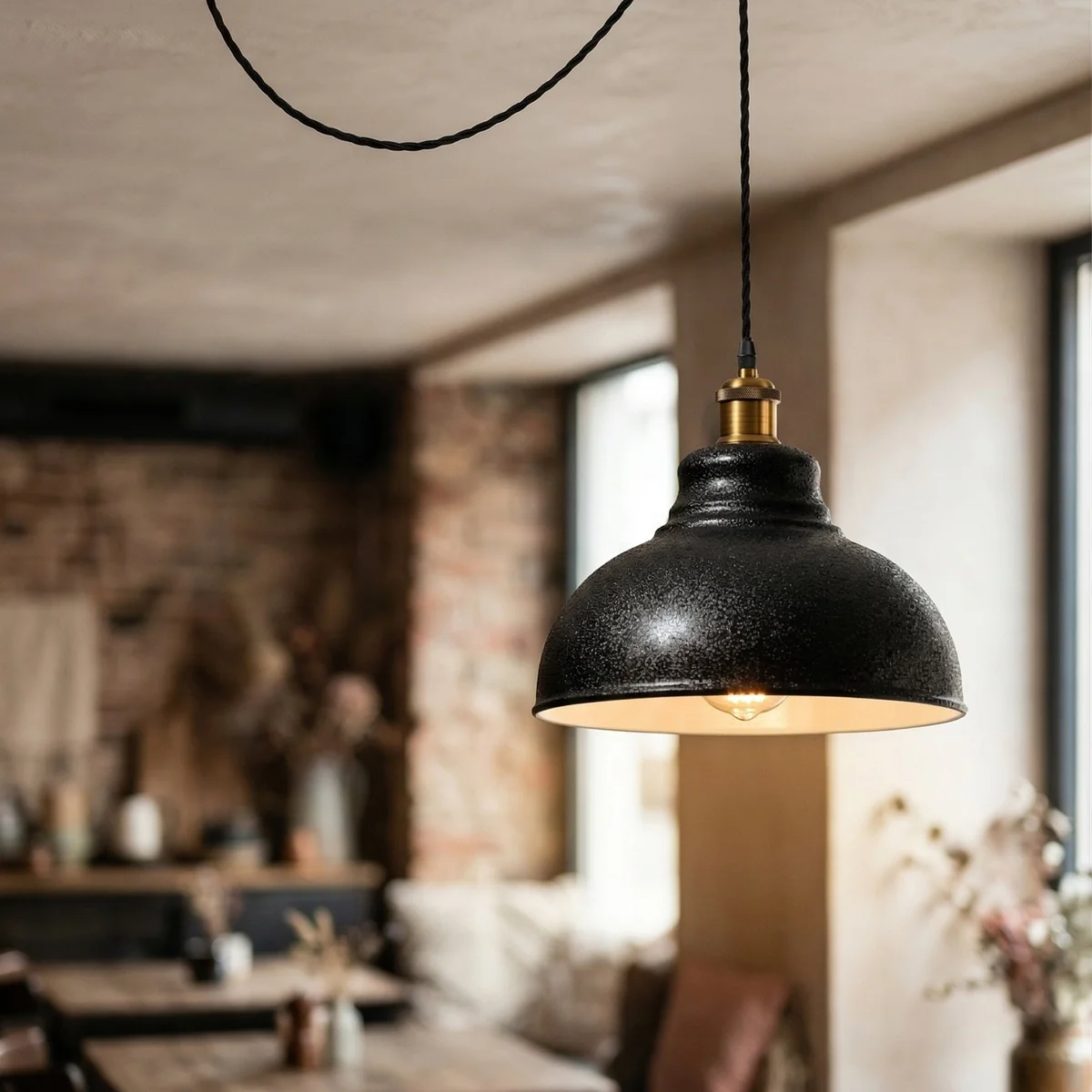 Black industrial pendant light with curvy metal shade, white interior, antique bronze holder, and adjustable twisted cable